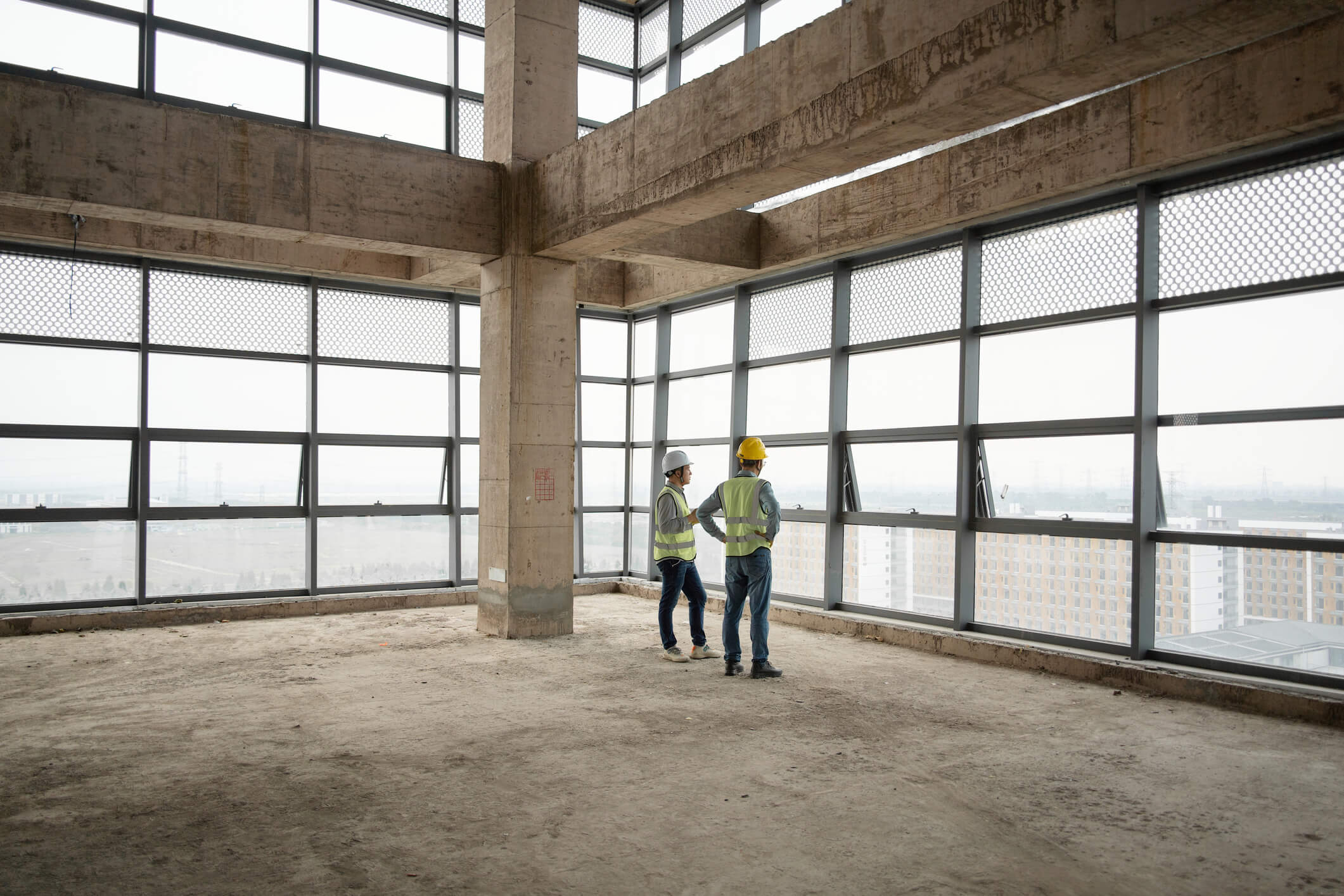 Two construction workers stand at a job site