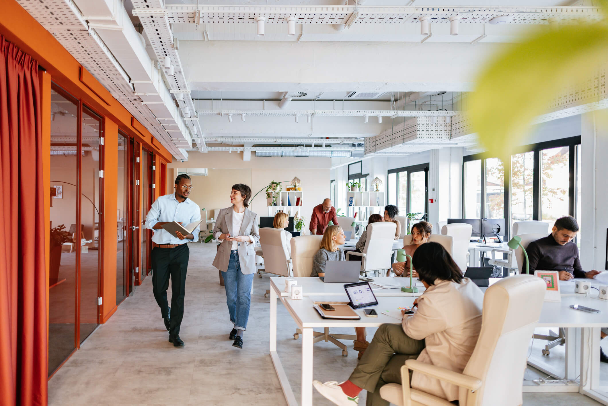 a man and woman walk through a busy, professional office