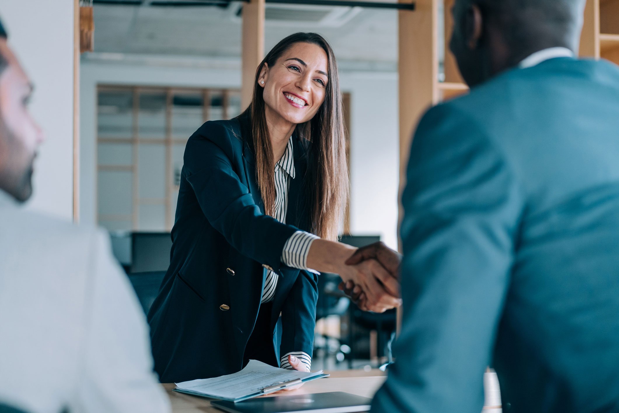 Smiling woman shaking hands inside an office