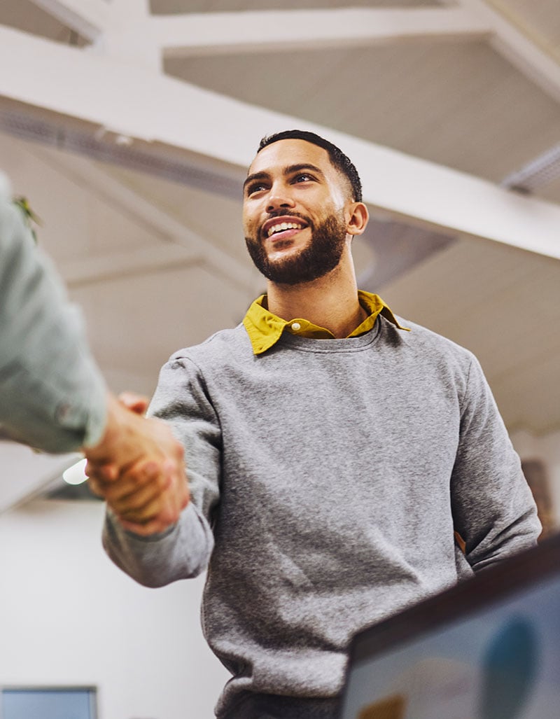 Smiling man shaking hands inside an office