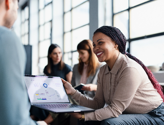 Woman smiling as she shows sales results on a laptop