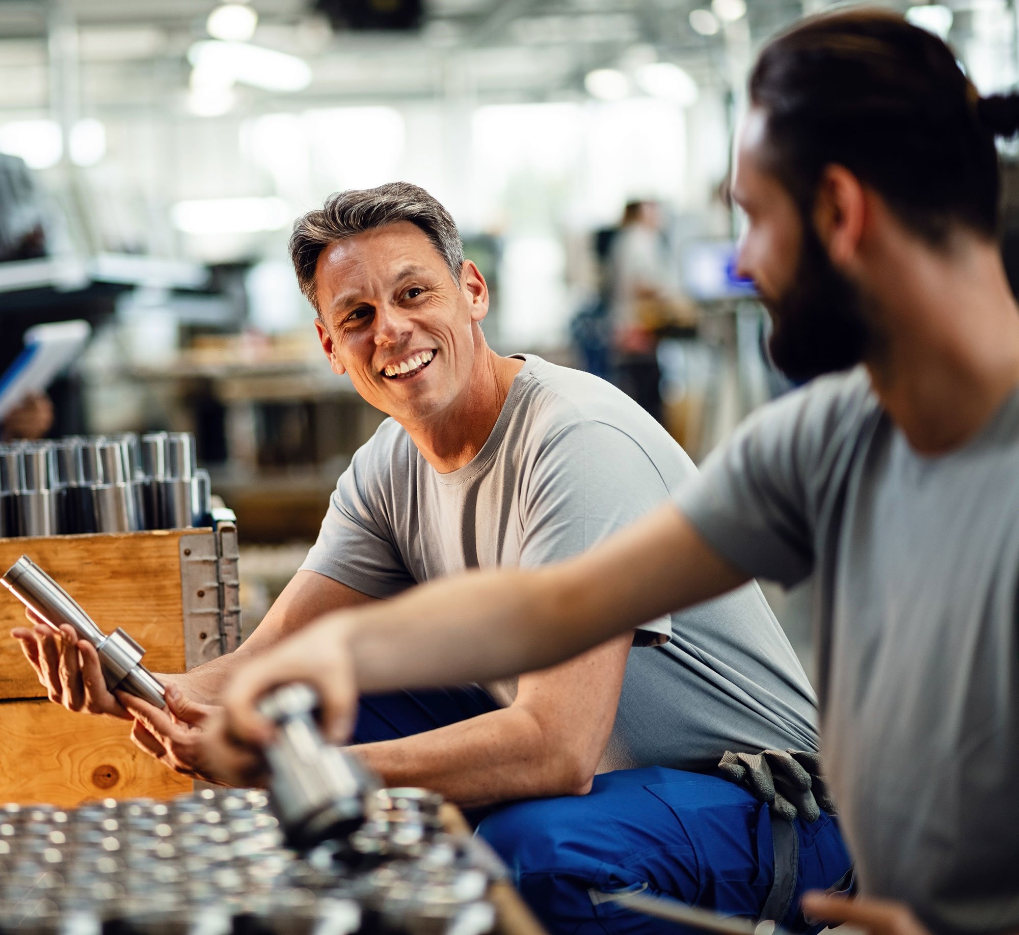 Two men seated next to each other in a manufacturing facility