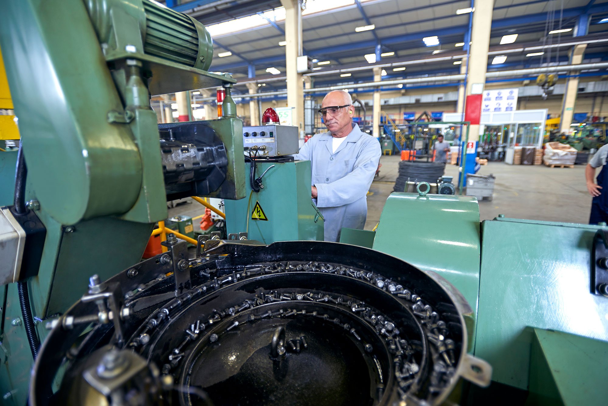 Man wearing safety glasses and ear plugs while working in a manufacturing facility