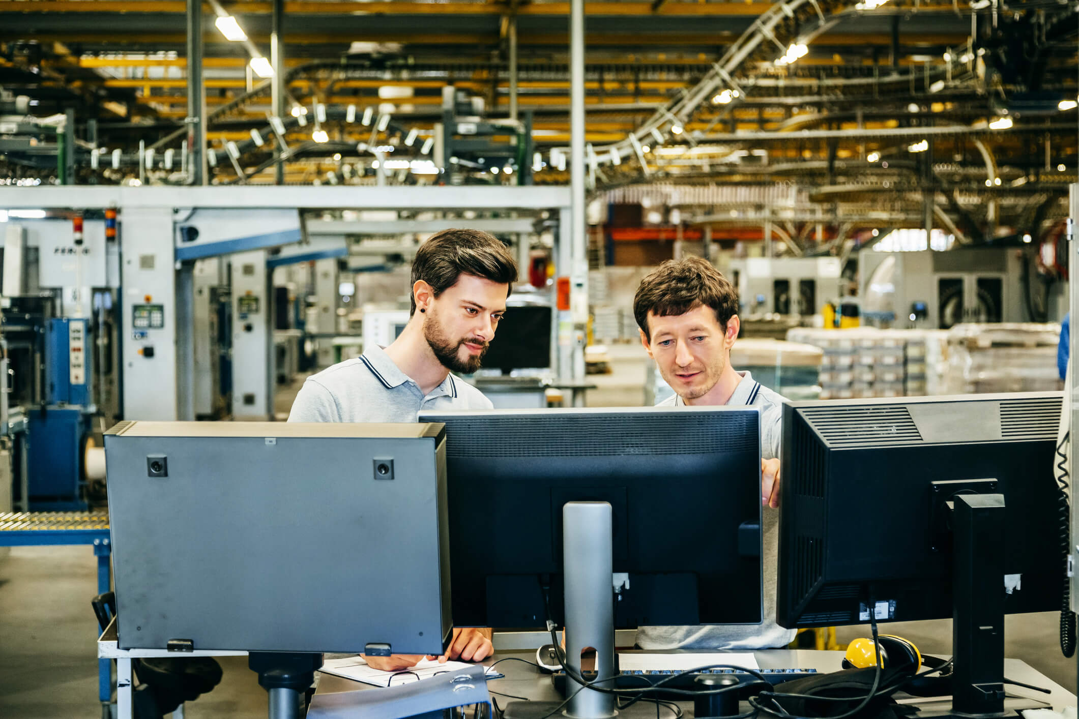 Two men working at computers in a manufacturing plant