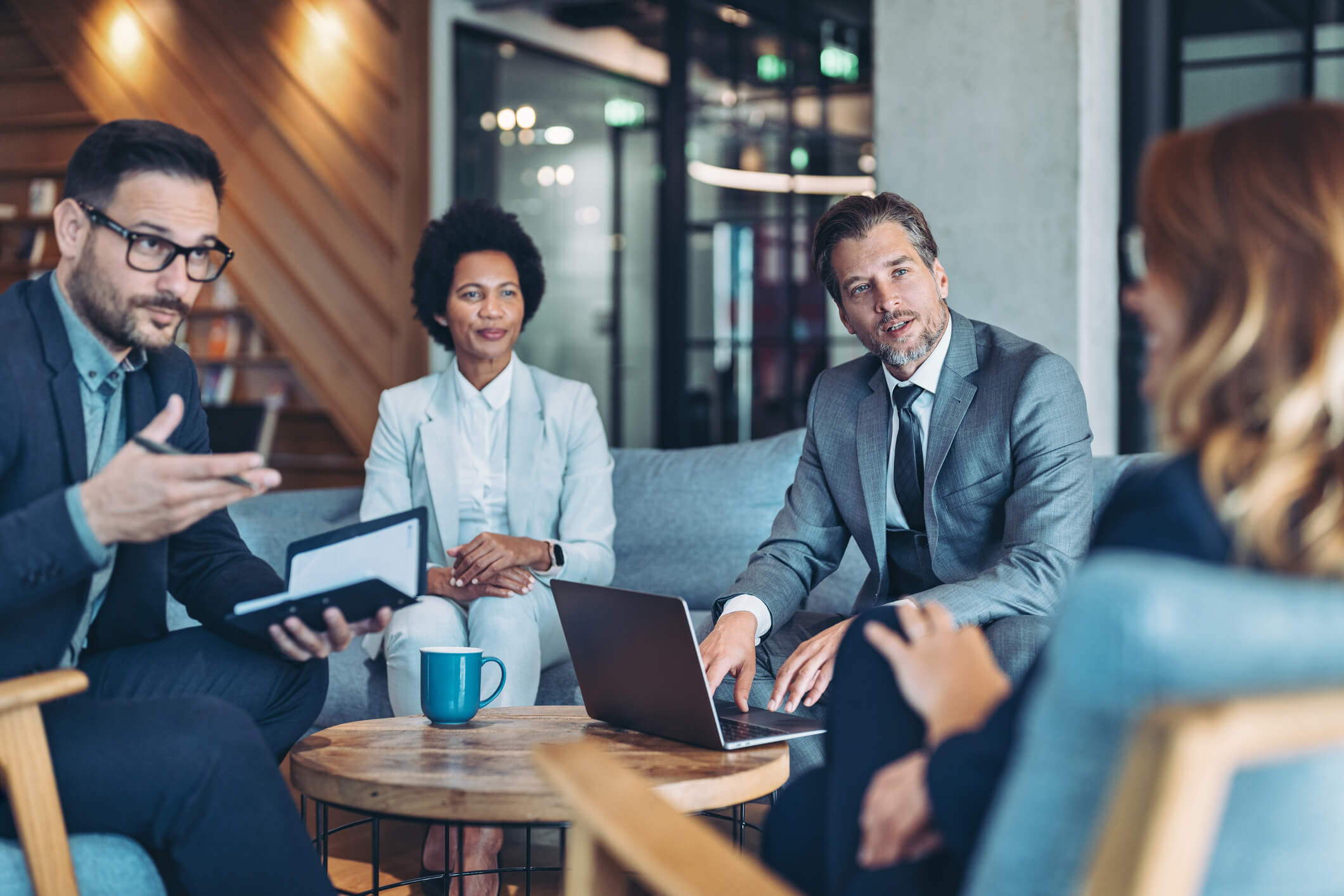 PE professionals discuss strategy around a coffee table with a laptop