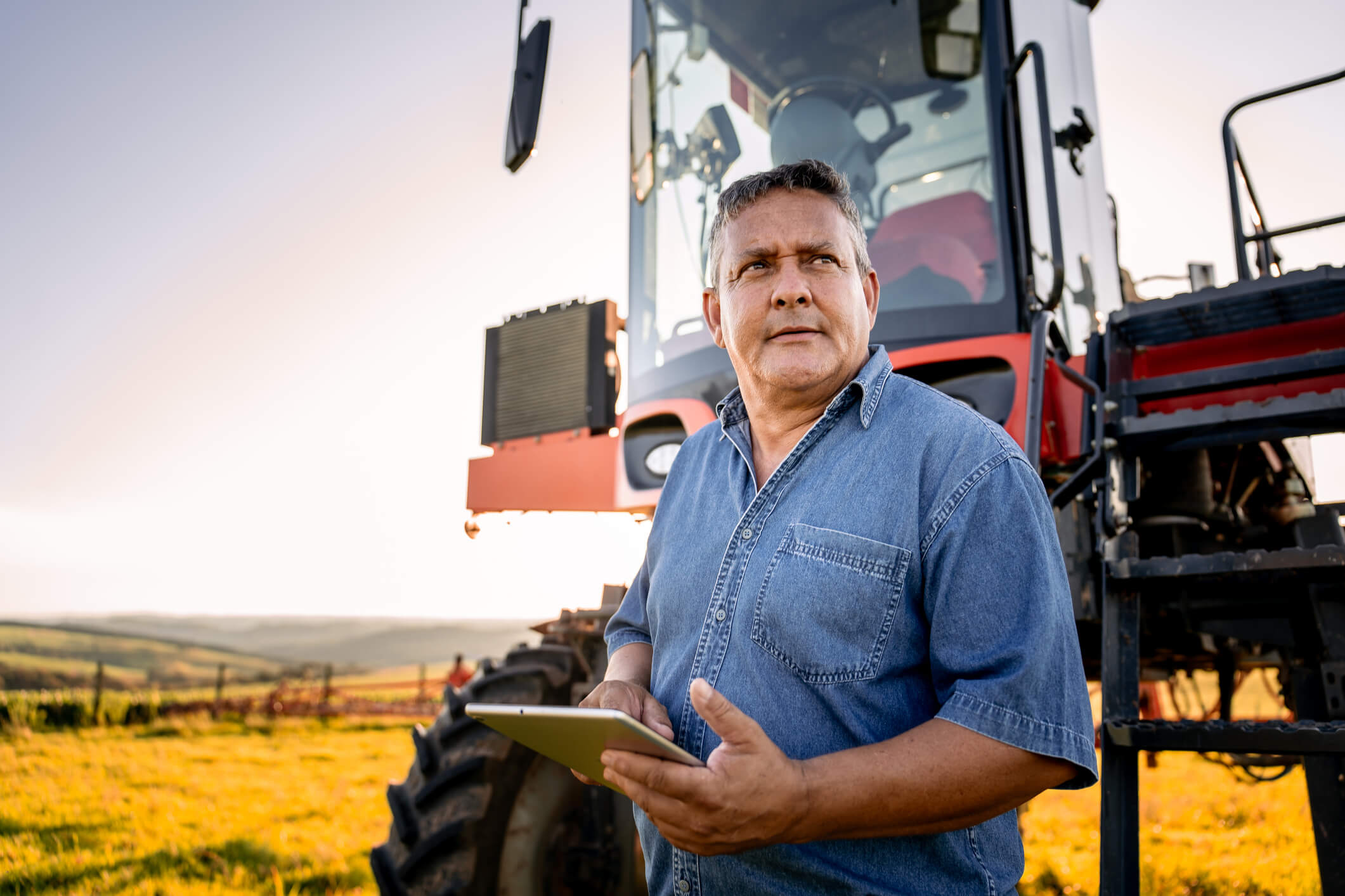 A man stands with an iPad in front of a tractor