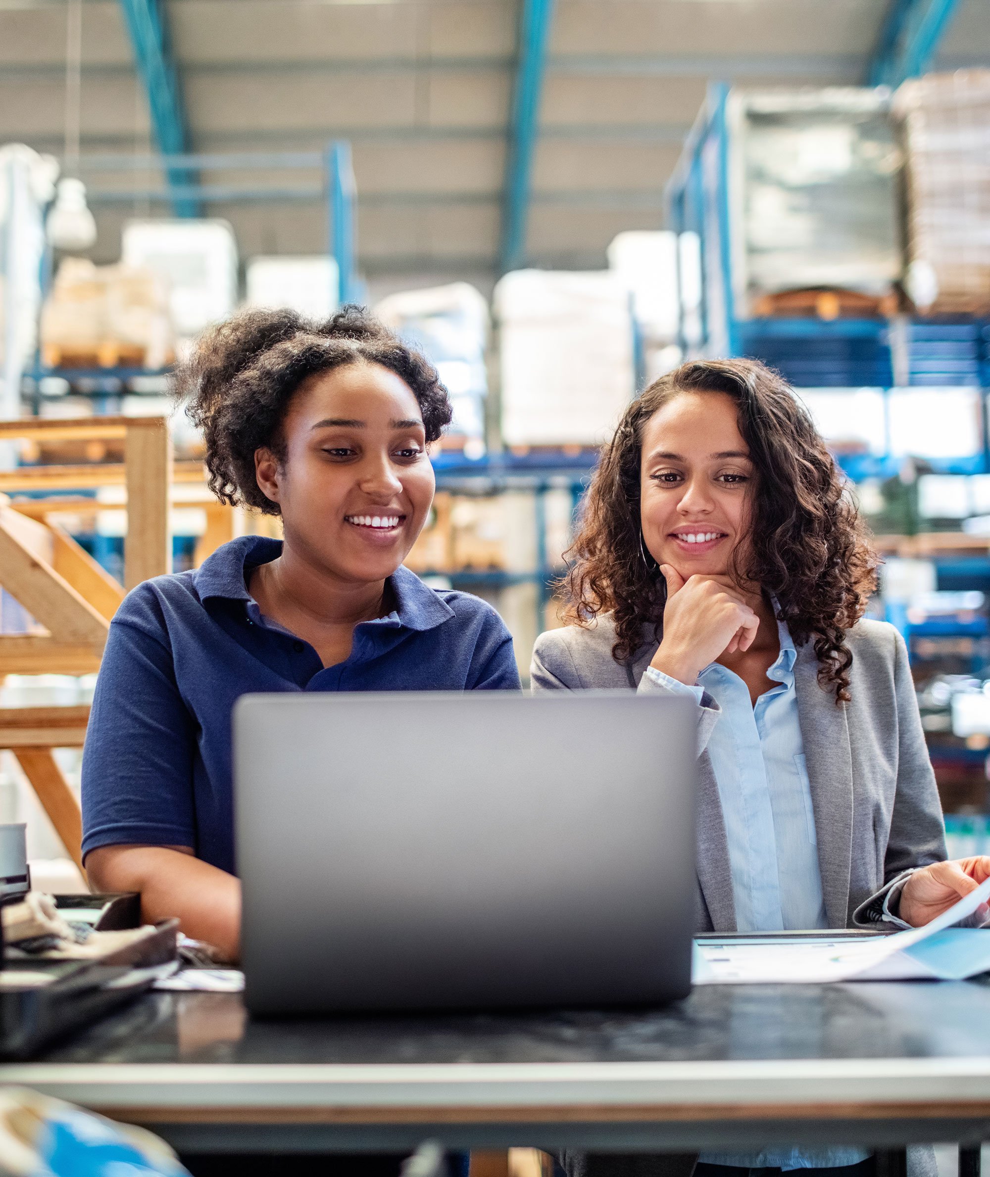 Two women standing and reviewing information on a laptop