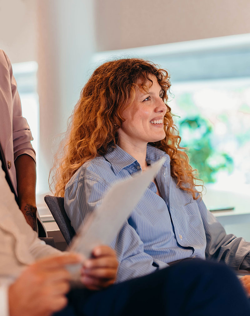 Woman seated and smiling during a presentation