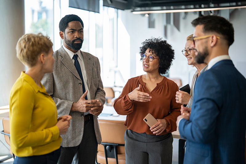Four professionally dressed people discussing strategy