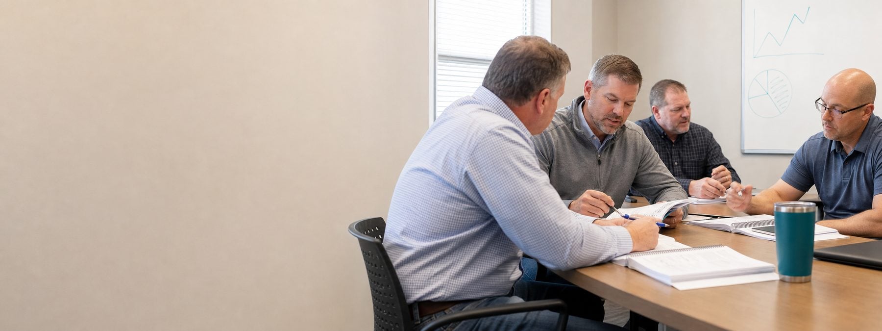 Two salespeople reviewing a printed sales skills assessment report at a training-room table