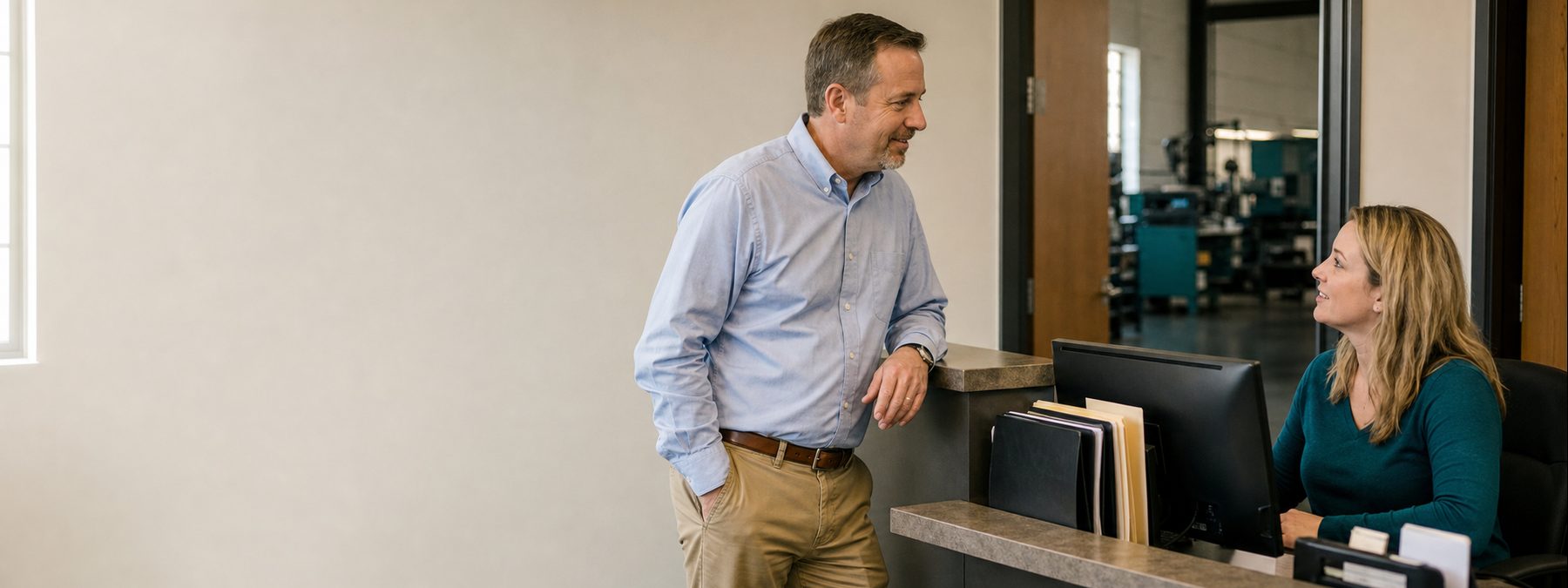 A salesperson speaking warmly with a gatekeeper at a company reception desk