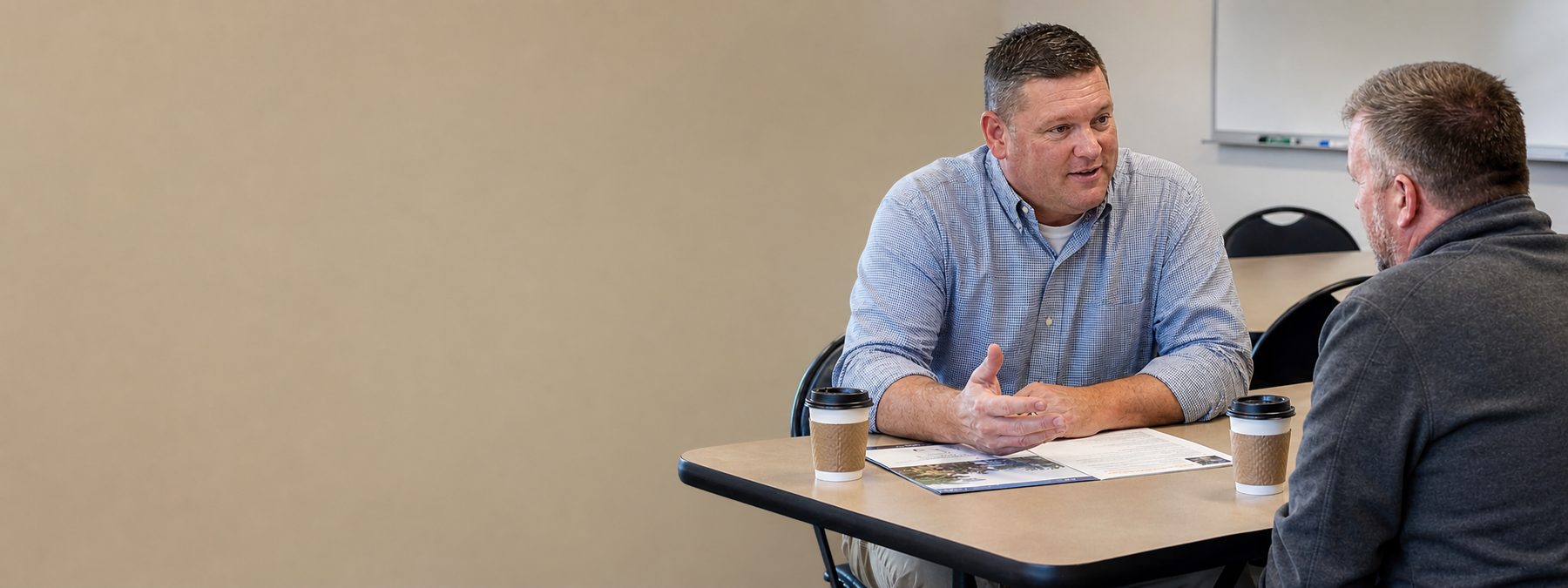 A salesperson introducing their company to a customer across a workshop table